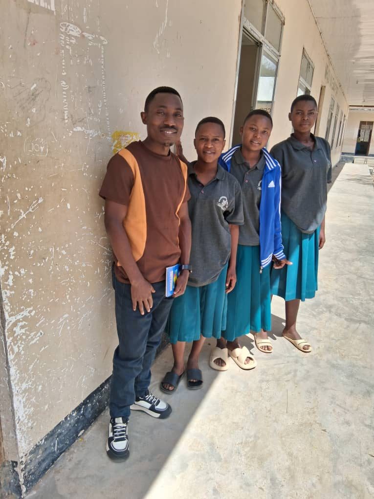 Benitho Kujela, left, with three secondary school scholarship students in a school corridor