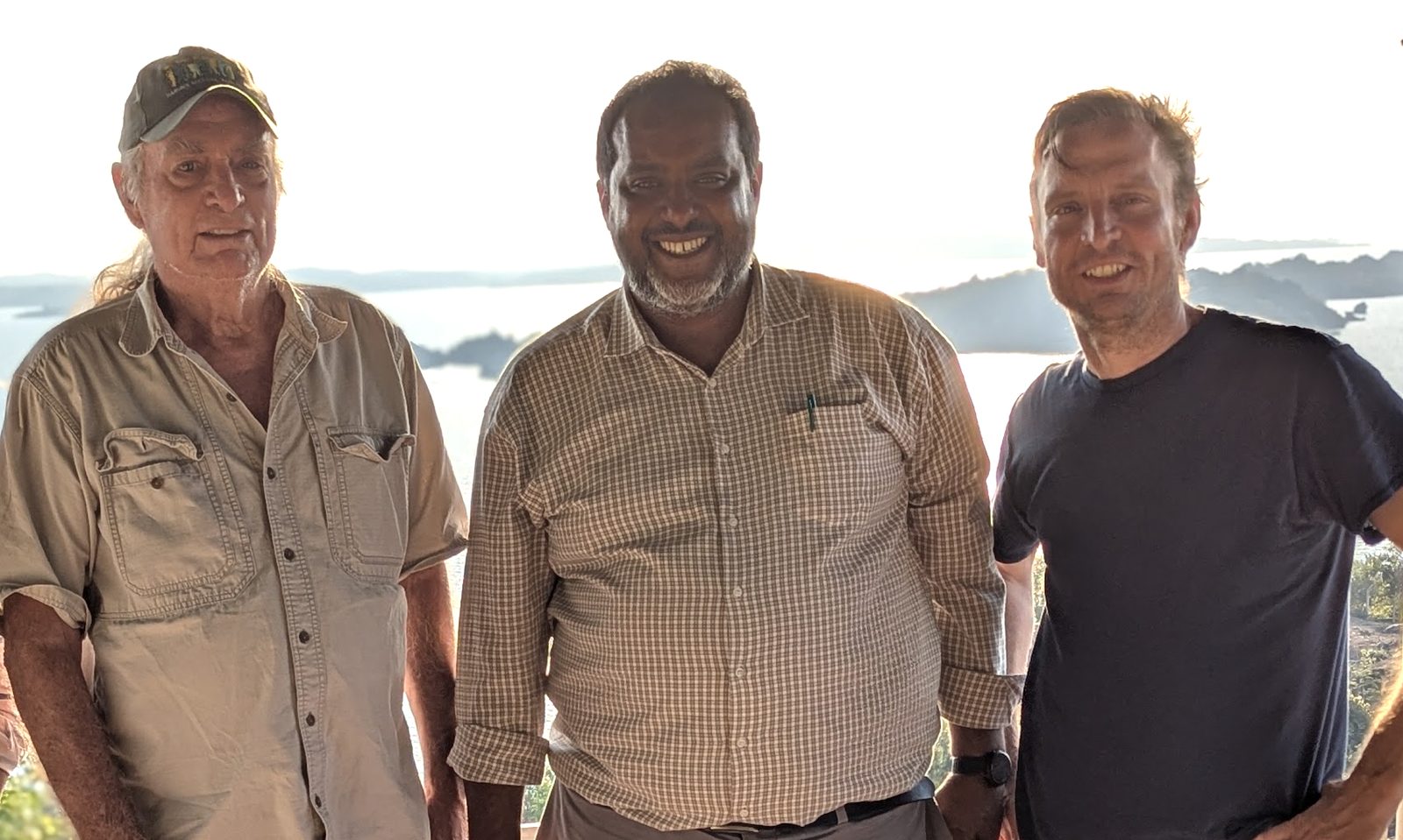 Three physicians smiling on a terrace overlooking Lake Victoria