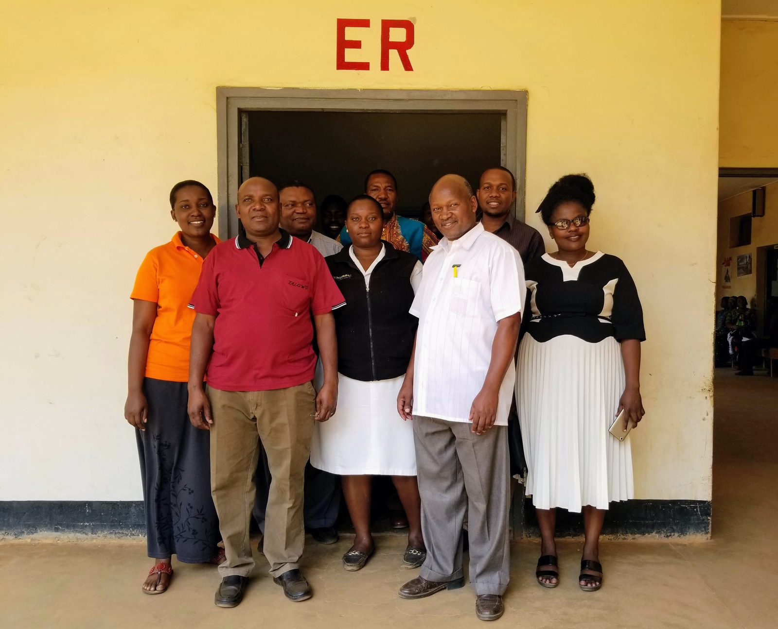 Hospital doctors and nurses standing together beneath a red ER sign